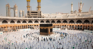 A wide-angle view of the Holy Kaaba in Makkah with pilgrims gathered to perform Umrah during the evening prayer.